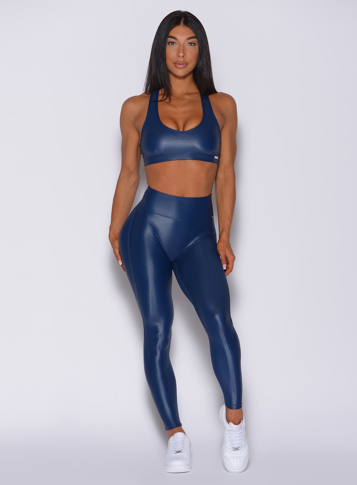 Model facing forward wearing our power gloss bra in navy blue color and a matching gloss leggings 
