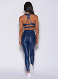 Back profile view of a model in our power gloss bra in navy and a matching gloss leggings