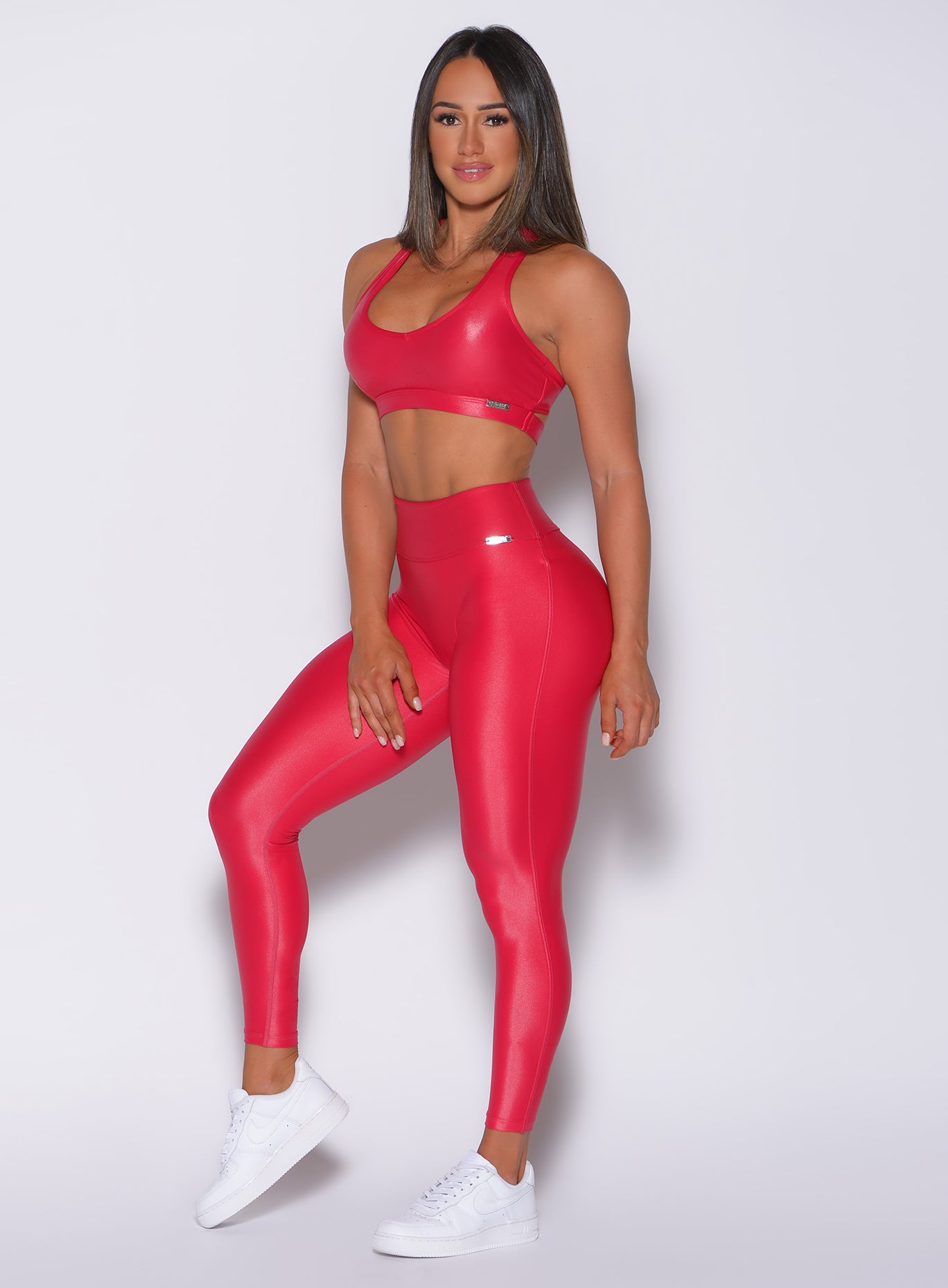 left side profile view of a model angled left wearing our red gloss leggings and a matching bra