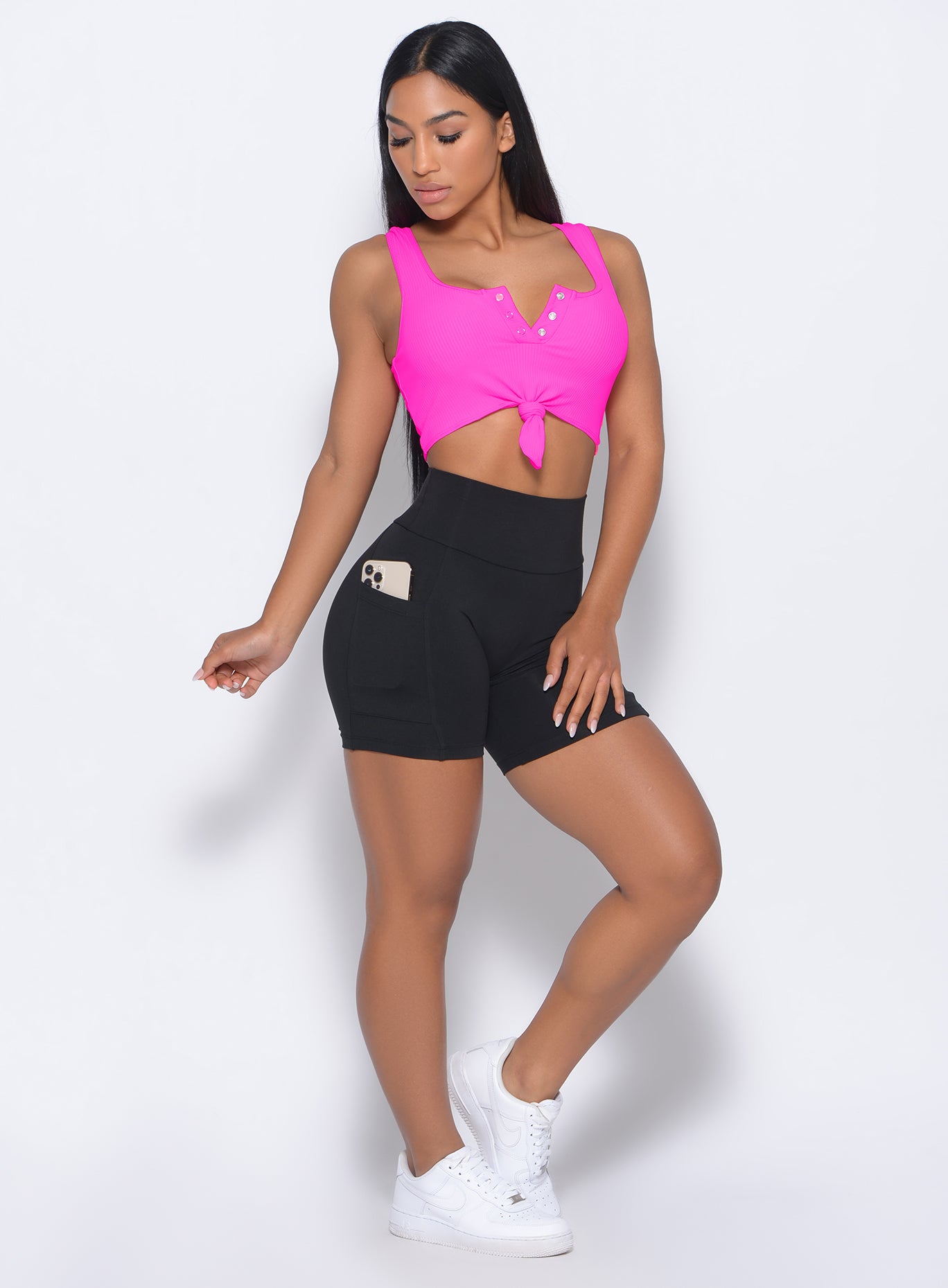 Front profile view of the model wearing our henley sports bra in neon pink and a black leggings 