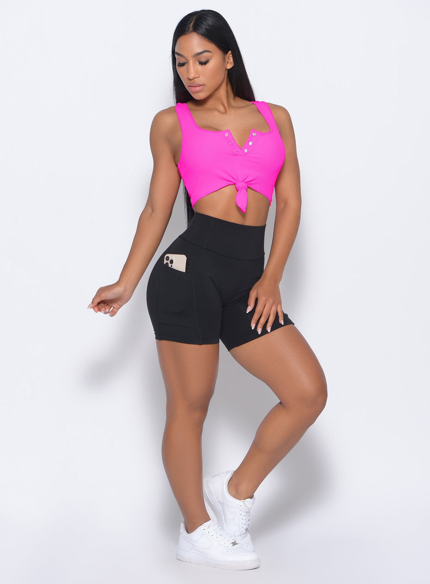 Front profile view of the model wearing our black pocket biker shorts and a neon pink bra