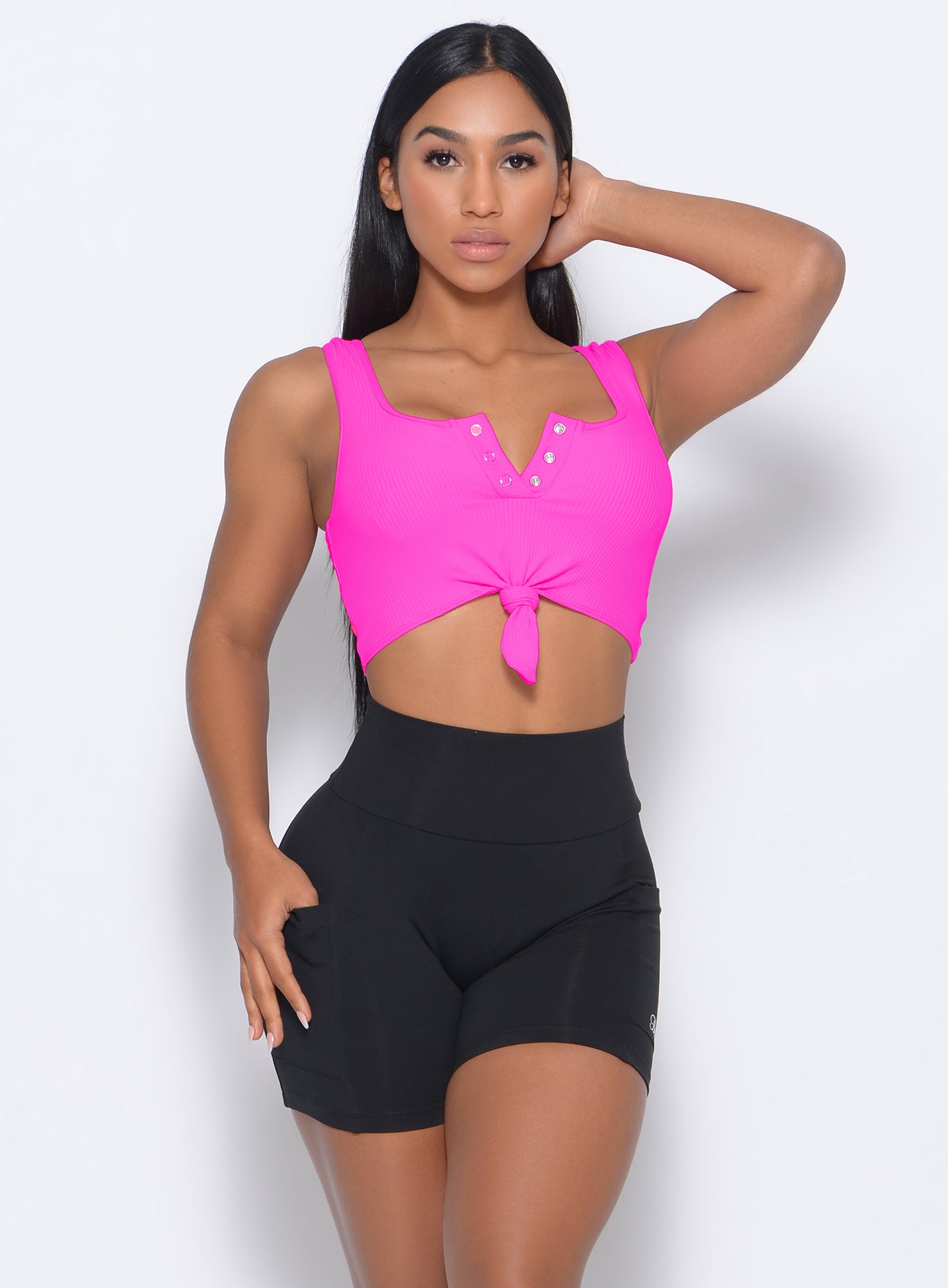 Front profile view of the model in our  henley sports bra in neon pink  and a black shorts 