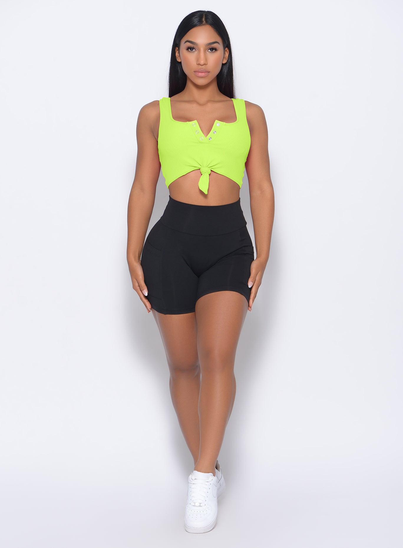 Model facing forward wearing our henley sports bra in neon yellow and a black shorts