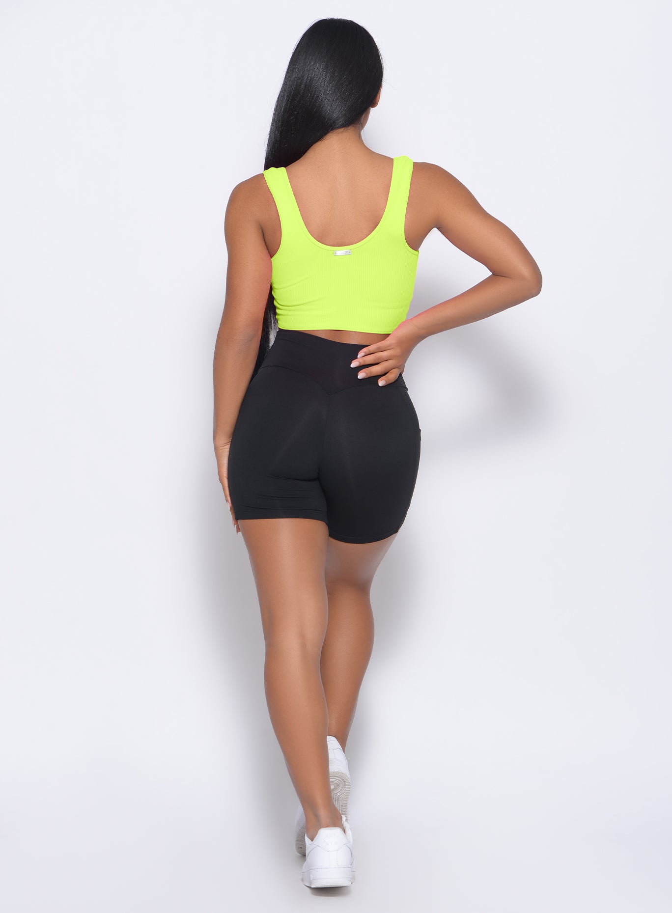 Back view of the model wearing our henley sports bra in neon yellow and a black shorts