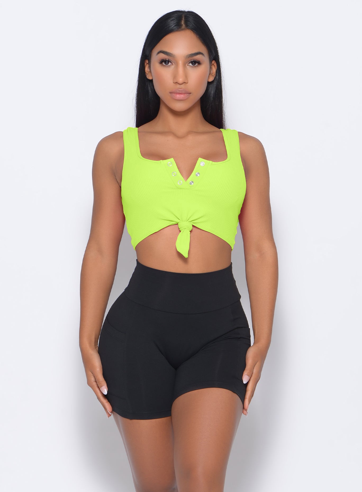 Front profile view of the model in our henley sports bra in neon yellow and a black shorts 