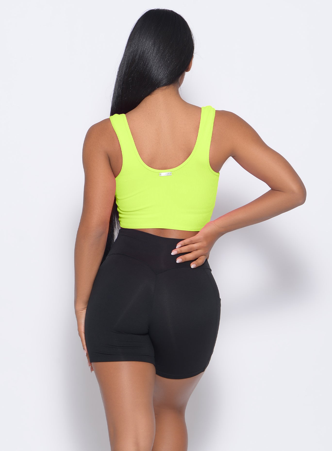 Back profile view of the model in our henley sports bra in neon yellow and a black shorts