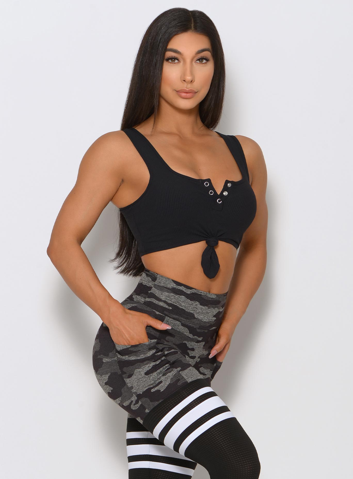 Right side view of the model angled right wearing our black henley tank with a camo print leggings