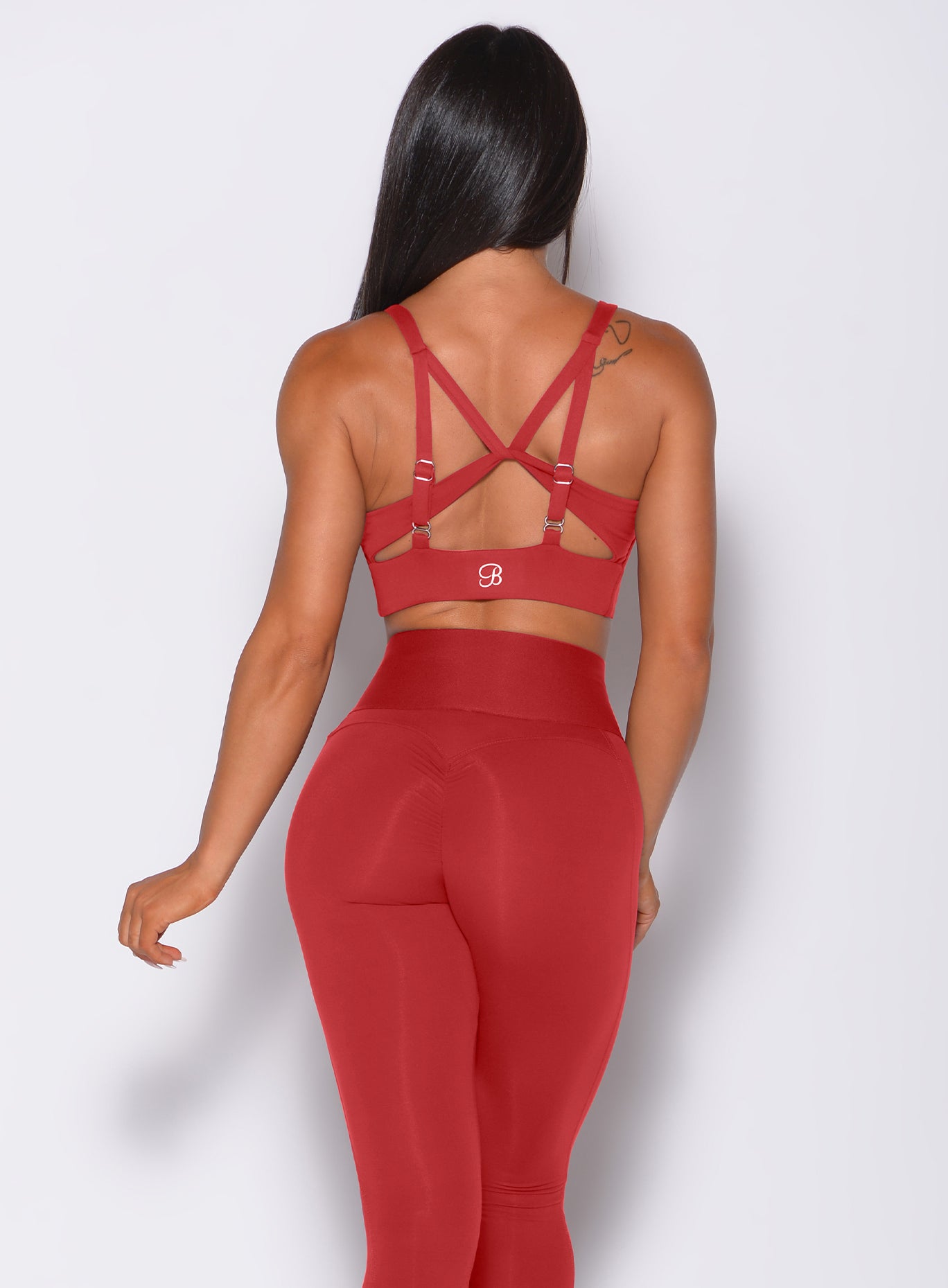 Back profile view of a model in our impact sports bra in sunset red and a matching leggings