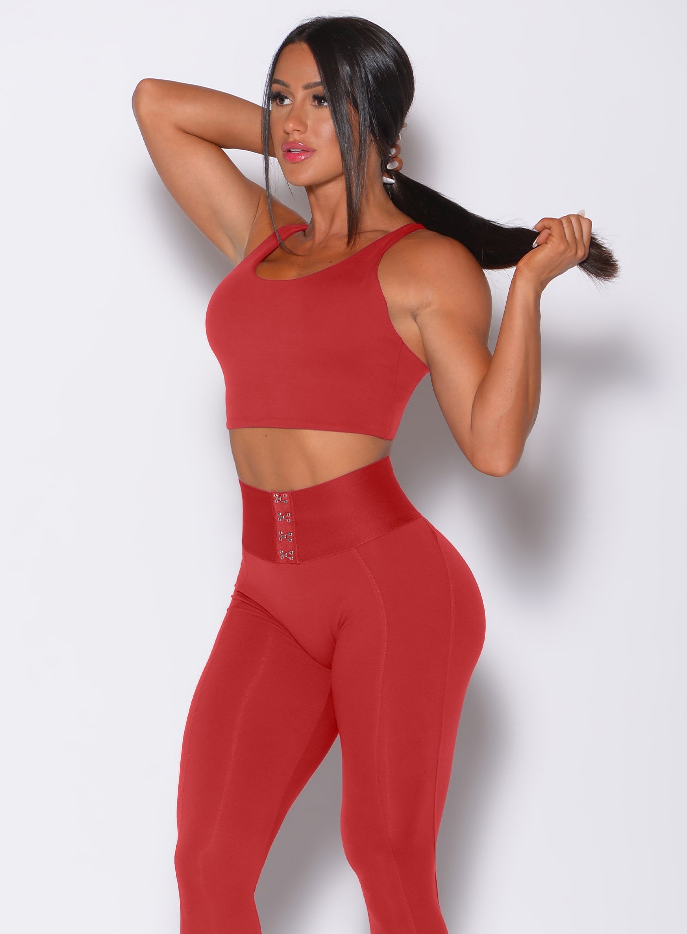 Left side profile view of a model angled left wearing our impact sports bra in sunset red and a matching leggings 
