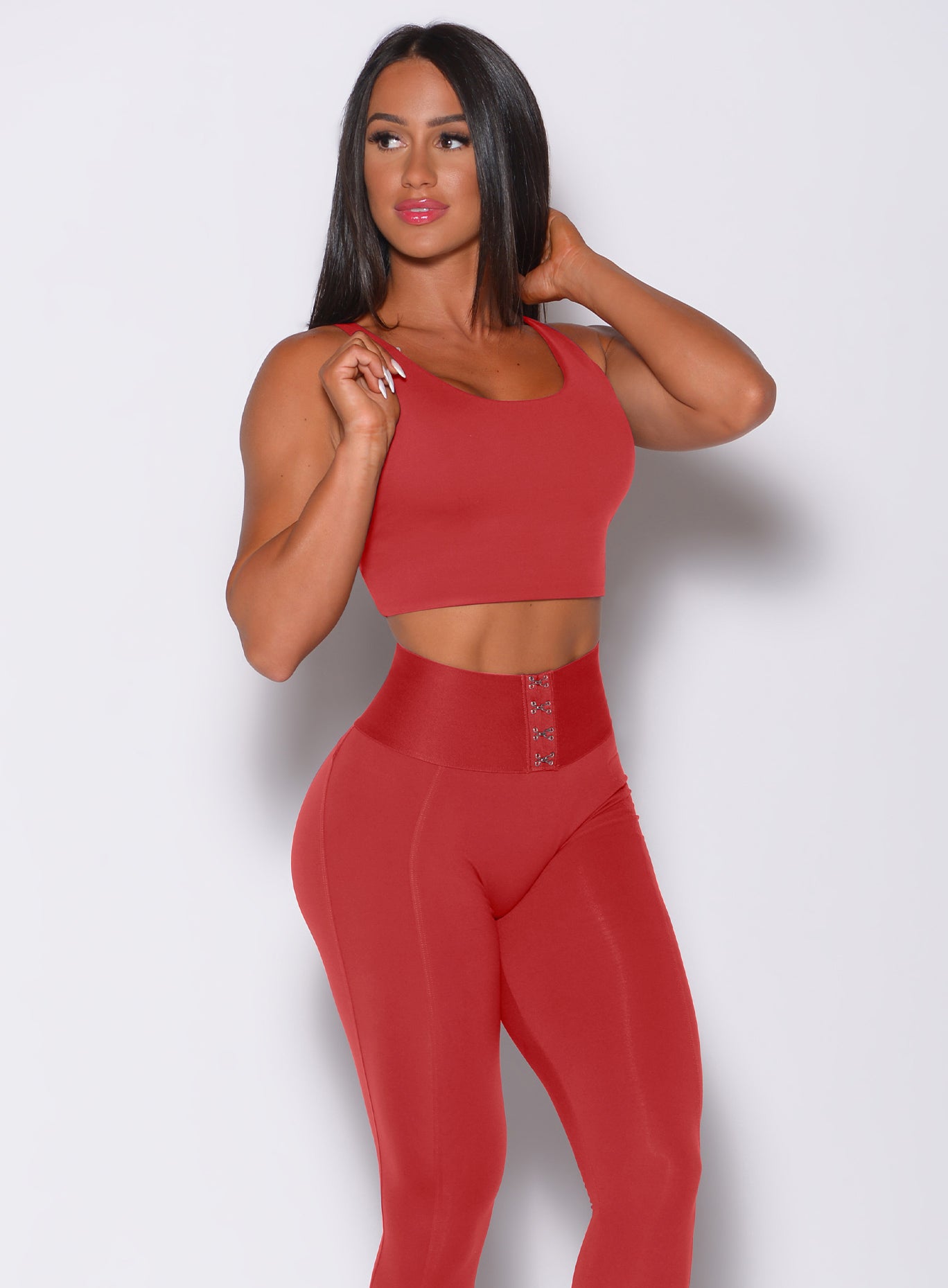 Right side profile view of a model angled right wearing our impact sports bra in sunset red and a matching leggings