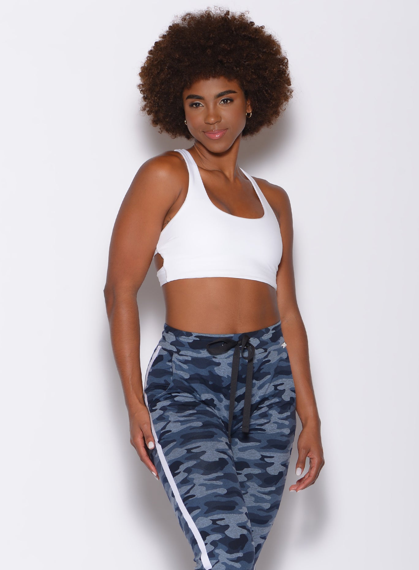 Front profile view of a model wearing our white back it up bra and a blue camo joggers