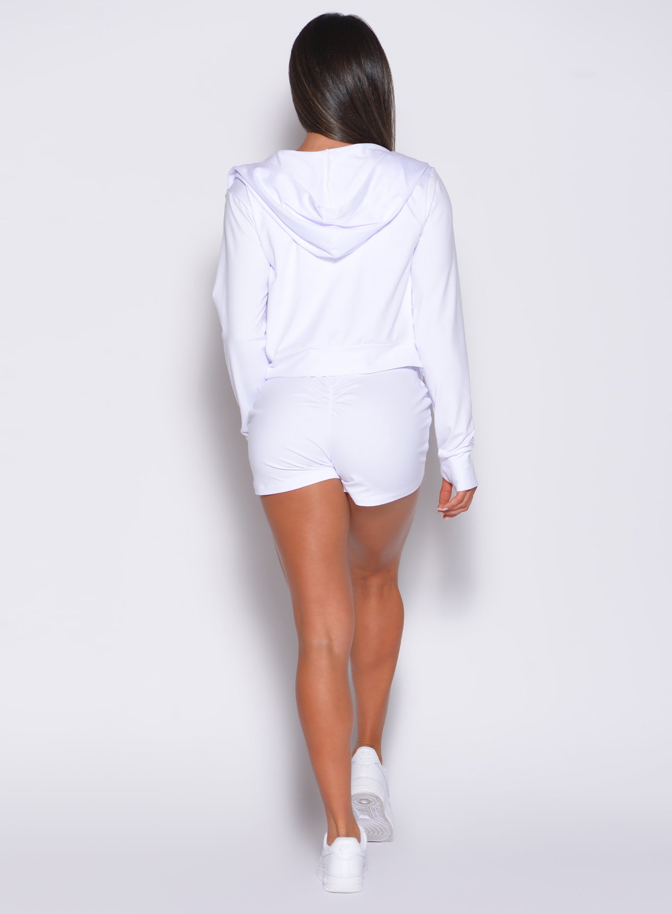 Back profile view of the model wearing our white joggers shorts and a matching hoodie