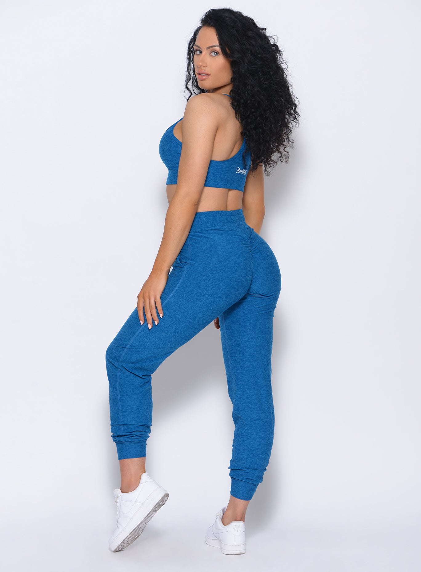 Left side view of the model wearing our Relax Sports Bra in azure color and a matching joggers  