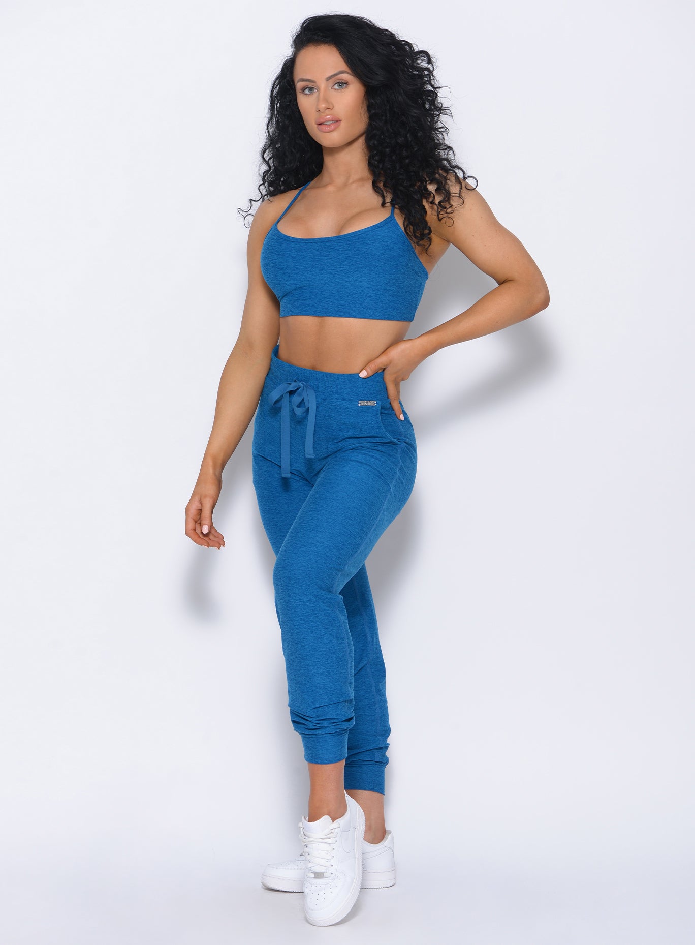 Front profile view of the model wearing our Relax Sports Bra in azure color and a matching joggers 