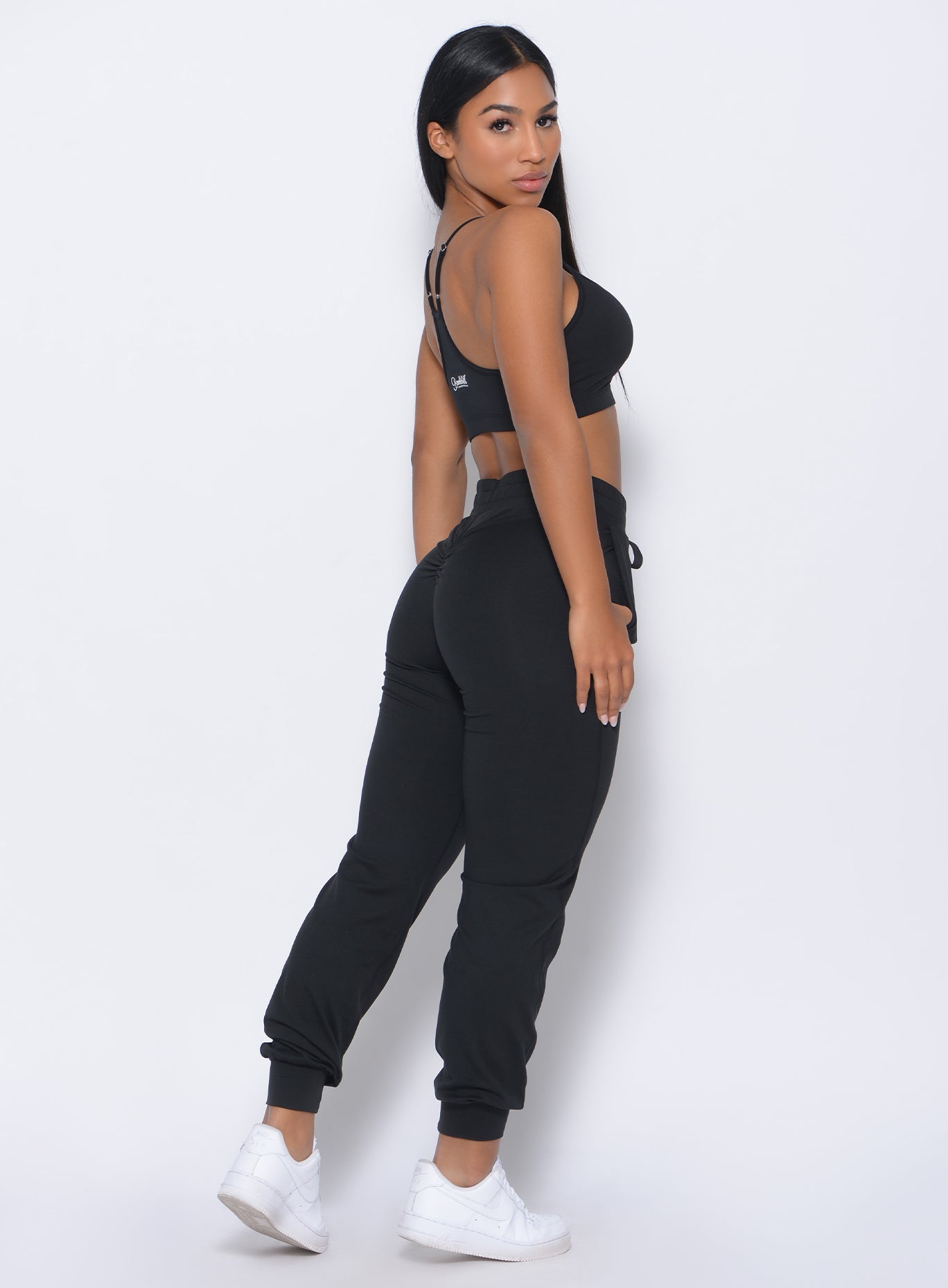 Right side view of the model facing to her right wearing our black Relax Sports Bra and a matching joggers