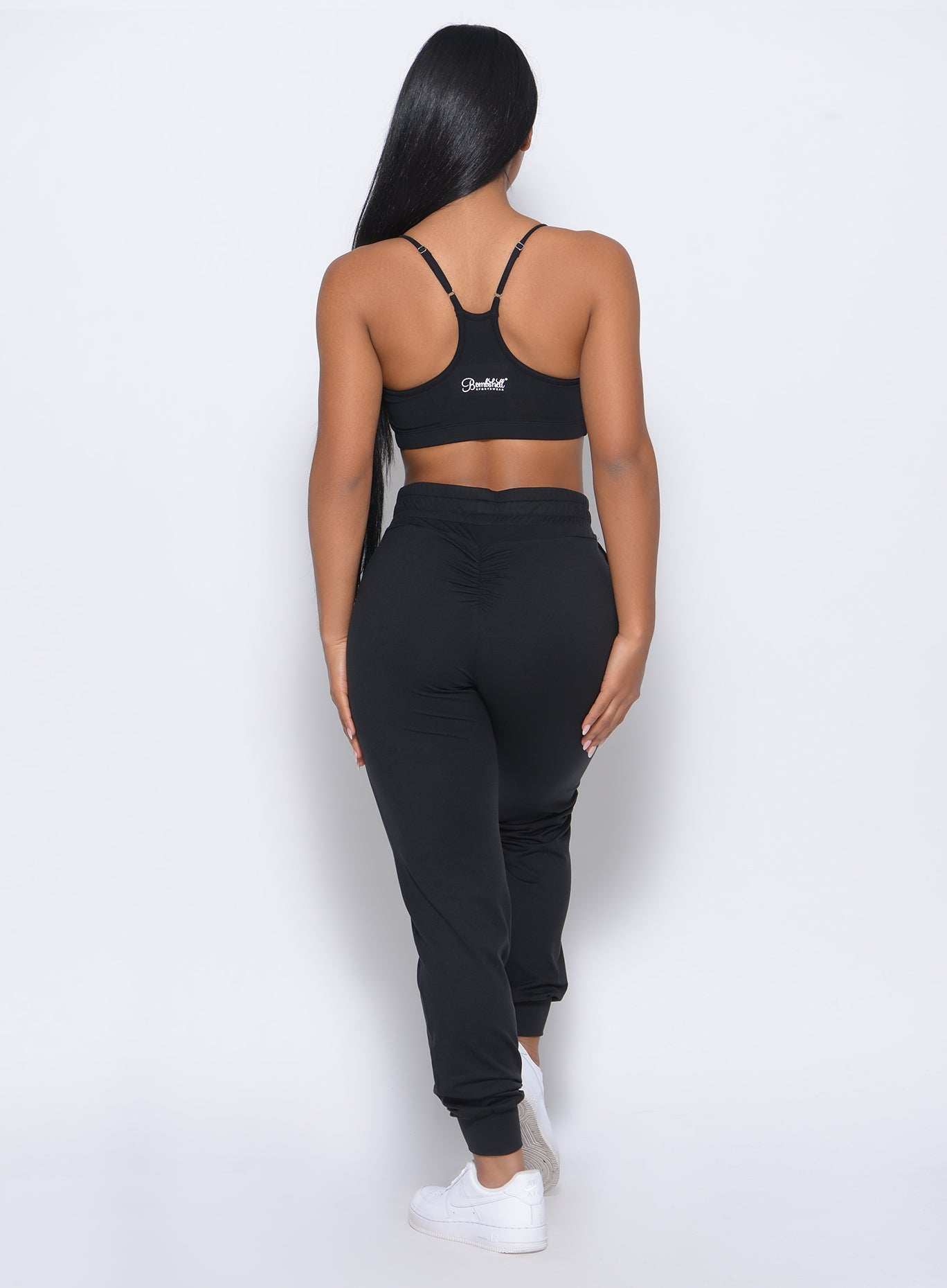Back profile view of the model in our black Relax Sports Bra and a matching joggers