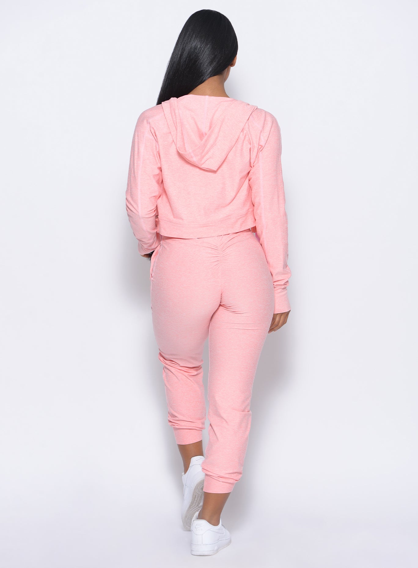 Back view of the model in our cozy joggers in peachy pink and a matching hoodie