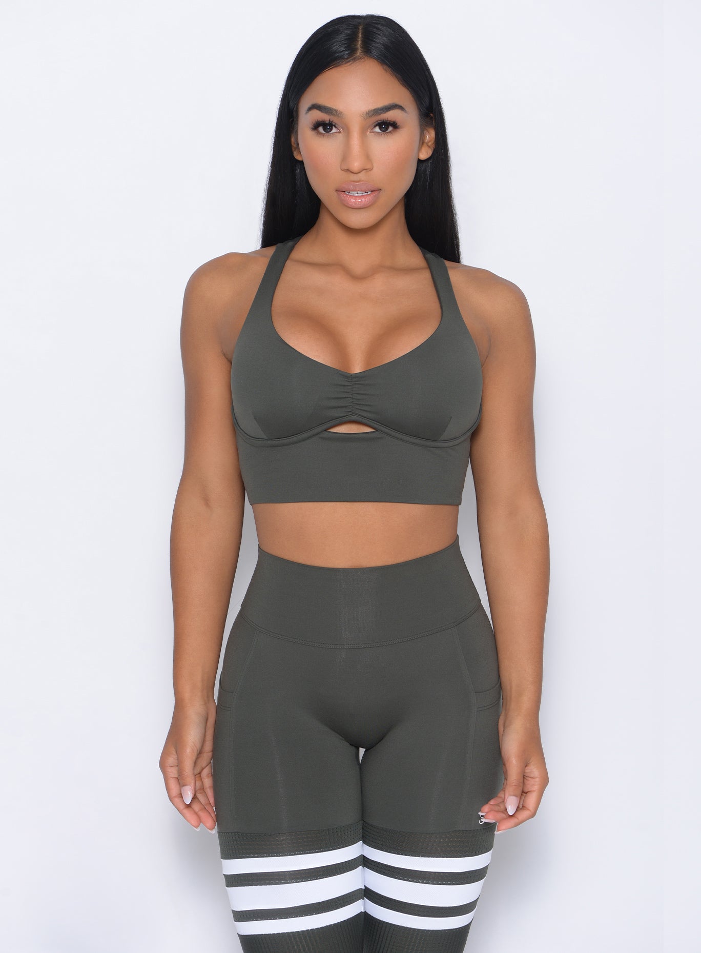 Front profile view of the model in our keyhole bralette in hunter green color and a matching leggings