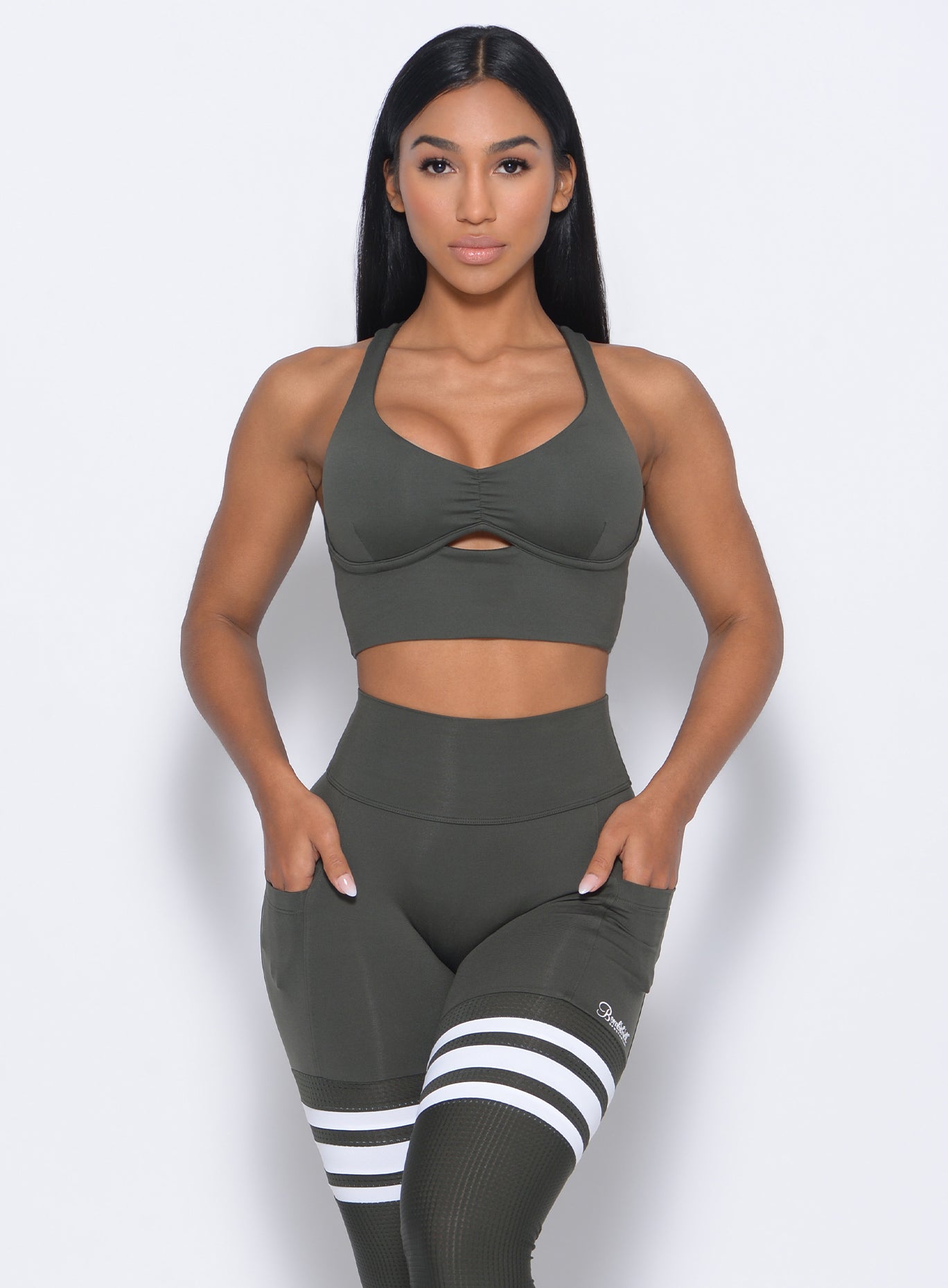 Front profile view of the model wearing our keyhole bralette in hunter green color and a matching leggings
