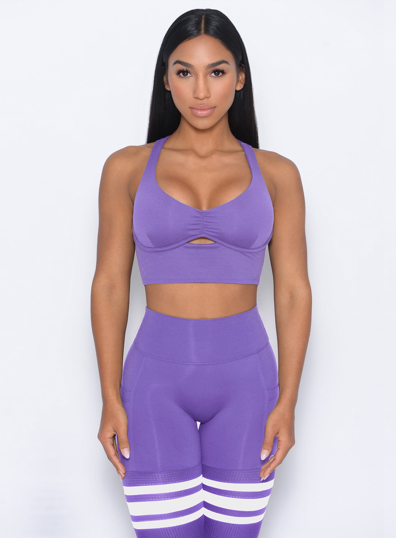 Front profile view of the model wearing our keyhole bralette in royal purple color and a matching leggings
