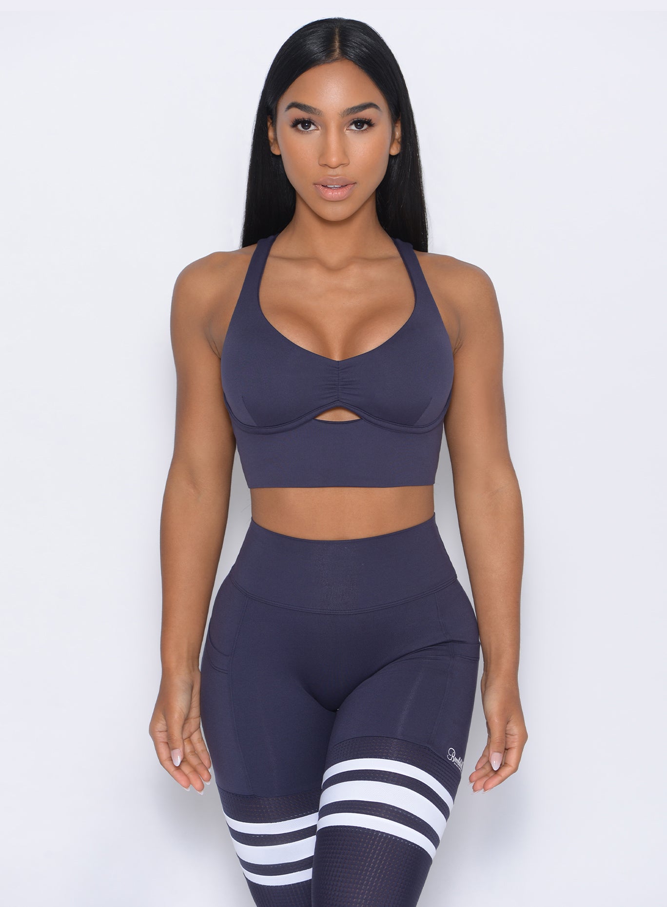 Front profile view of the model in our keyhole bralette in twilight blue color and a matching leggings