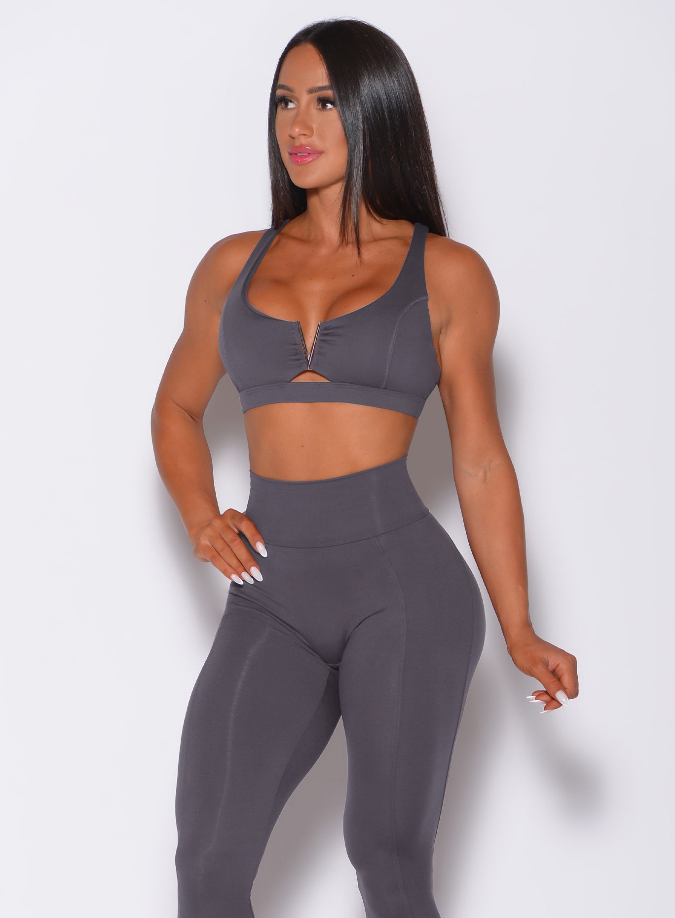 Front profile view of a model in our knockout sports bra in shadow color and a matching leggings 