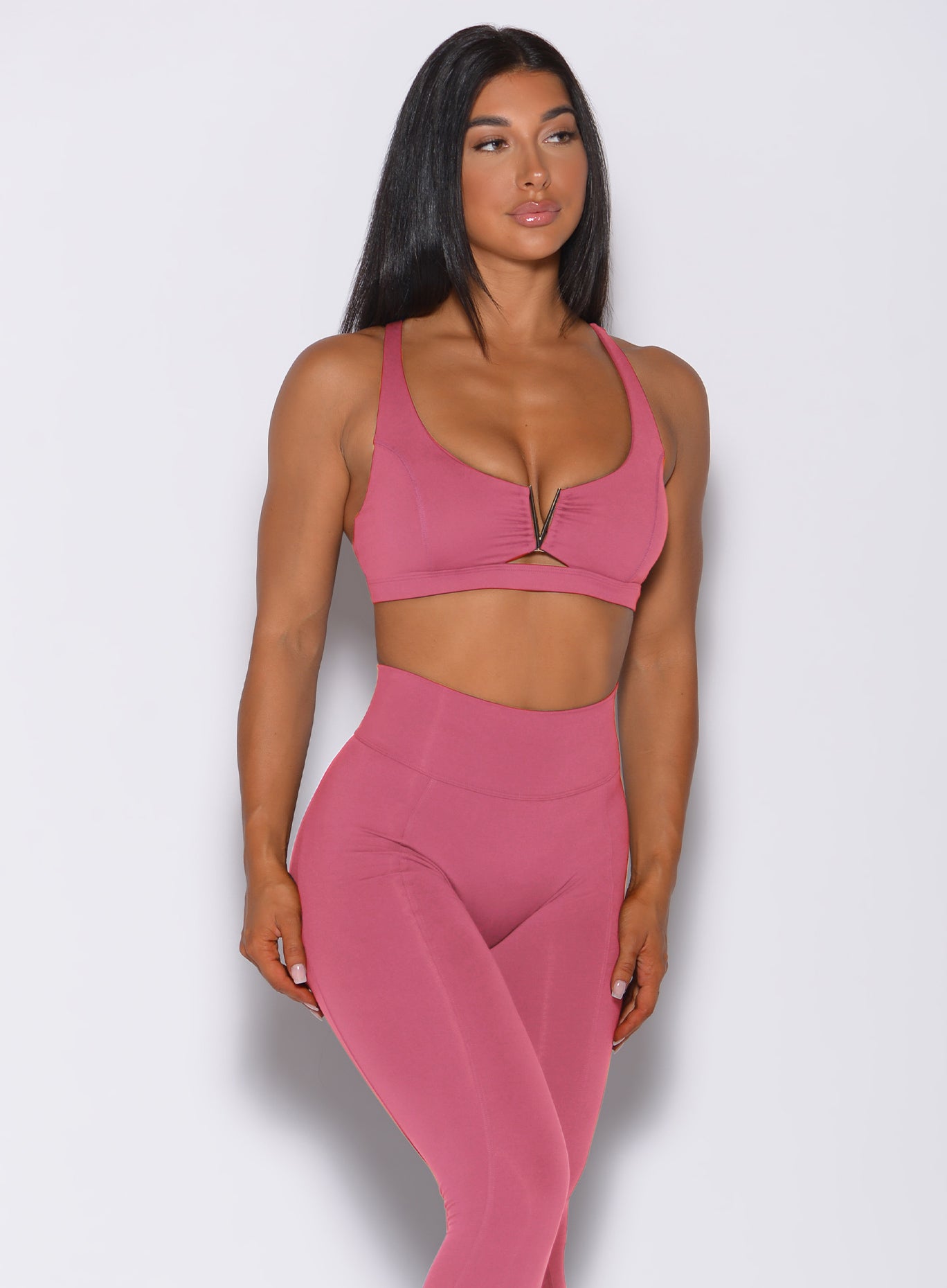 Front profile view of a model wearing our knockout sports bra in blush color and a matching leggings