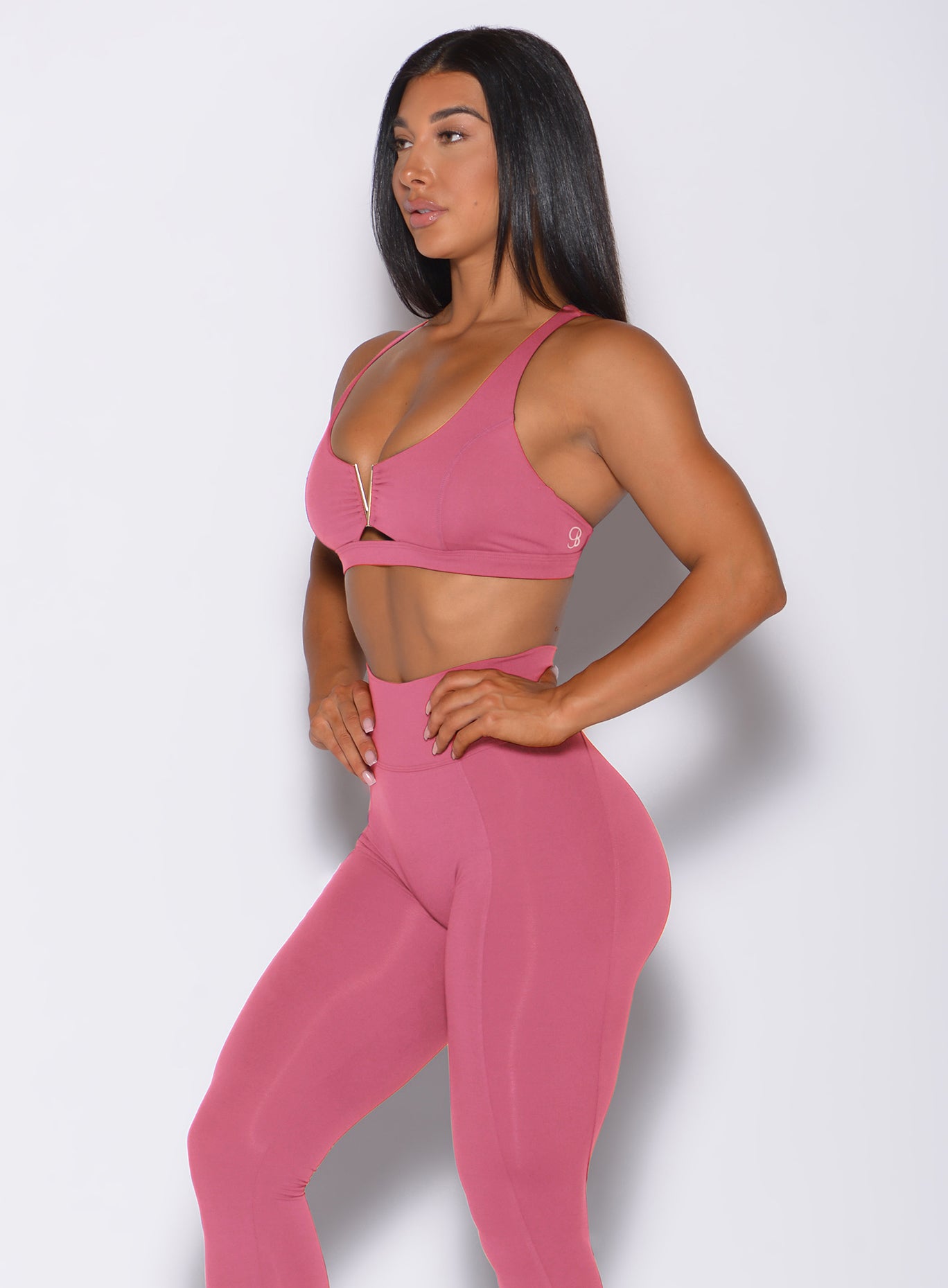 Left side profile view of a model angled to her left wearing our knockout sports bra in blush color and a matching leggings
