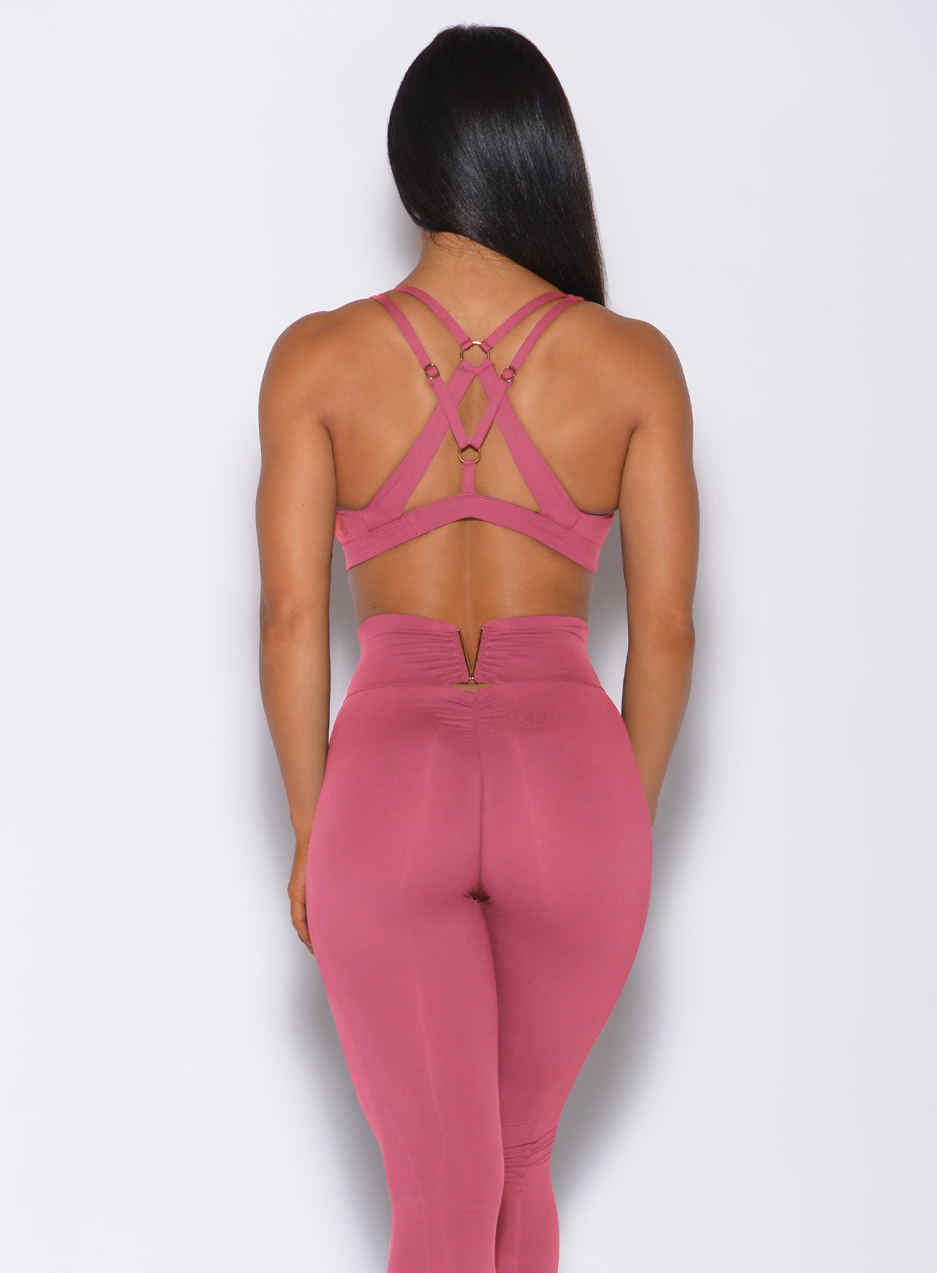 Back profile view of a model in our knockout sports bra in blush color and a matching leggings