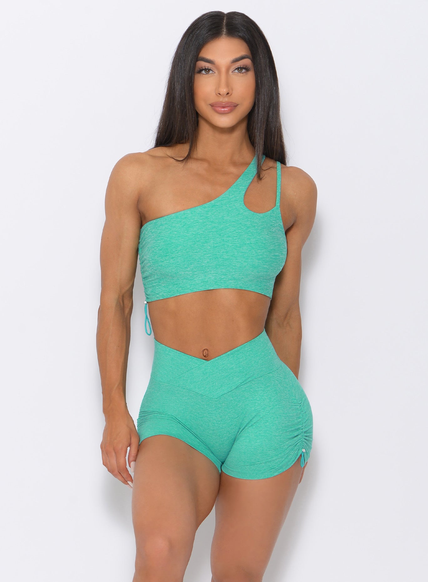 Front profile view of the model wearing our contour toggle shorts in mint color and a matching bra