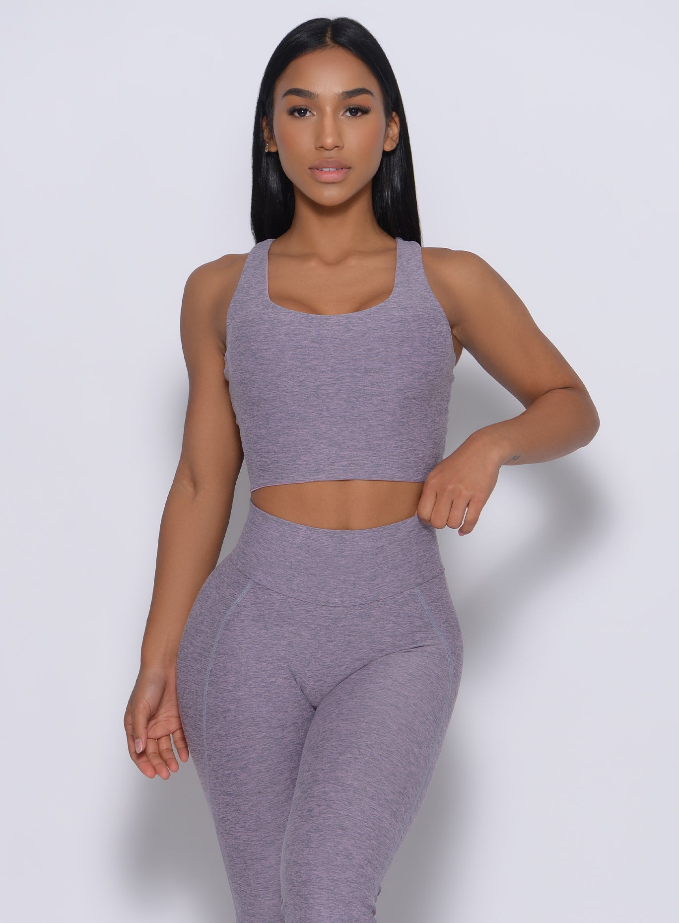 Front profile  view of the model wearing our reversible long bra in orchid color and a matching leggings