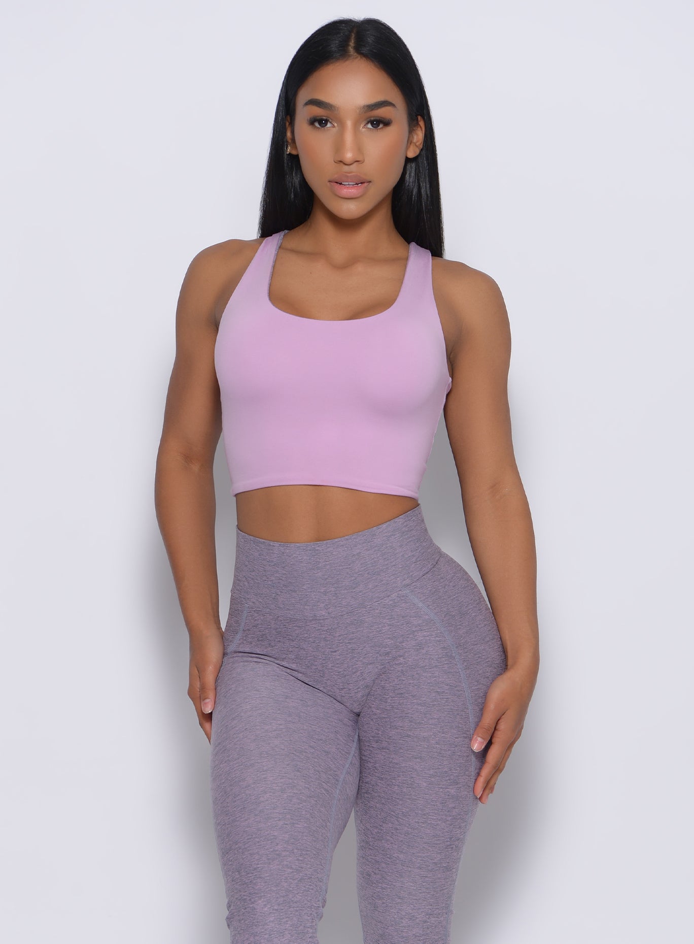 Front profile view of the model in our reversible long bra in orchid color and a matching leggings