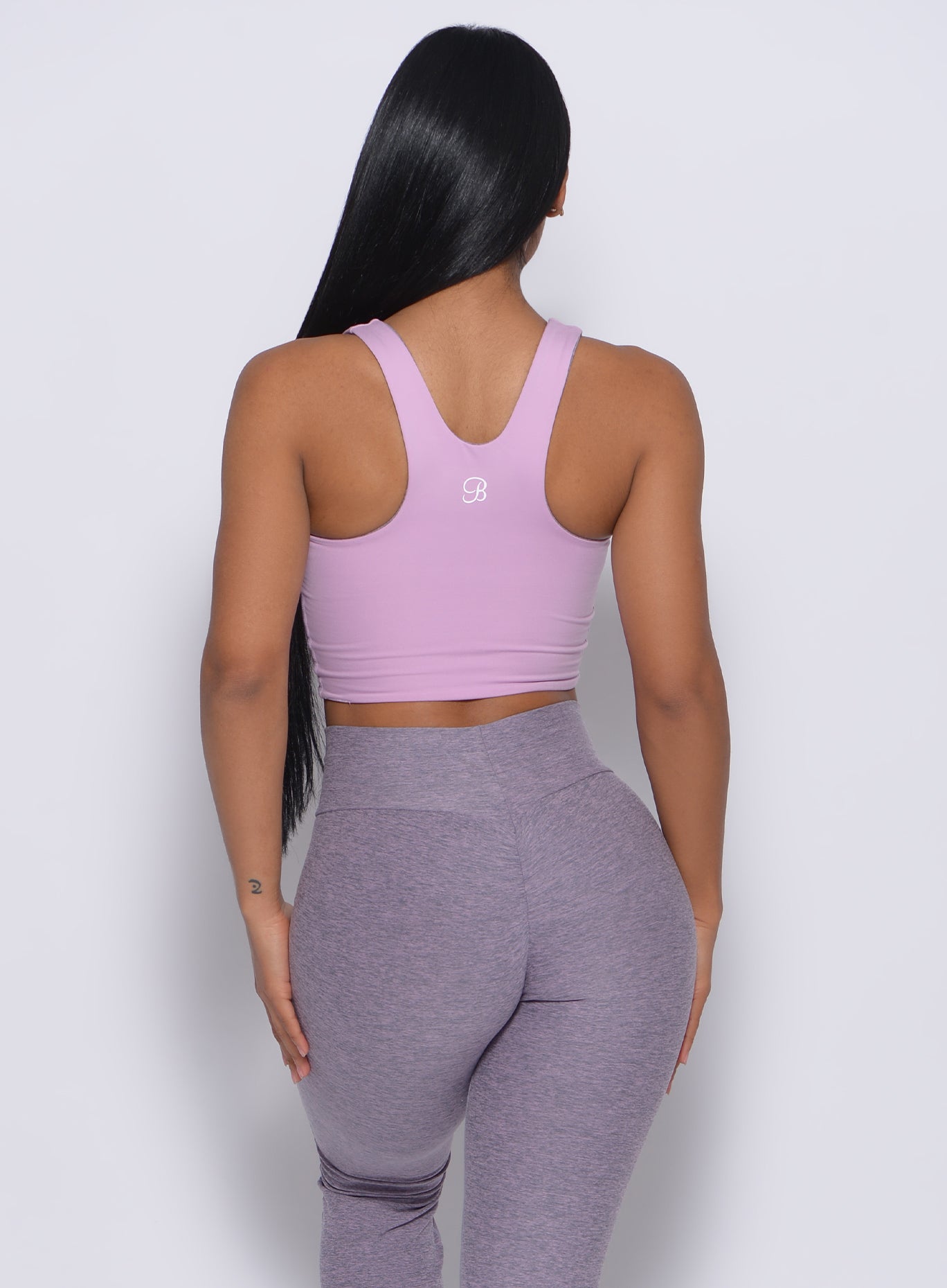 Back profile  view of the model in our reversible long bra in orchid color and a matching leggings