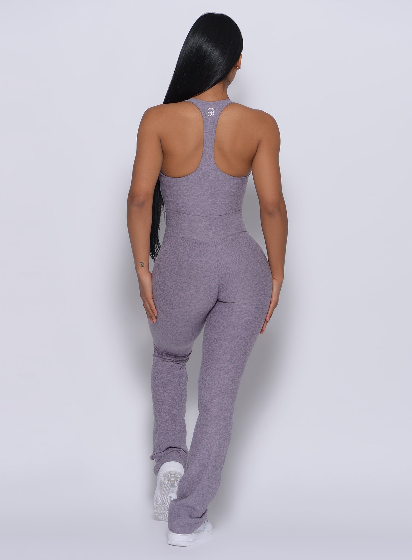 Back profile view of a model in our straight up leggings in orchid color and a matching bodysuit