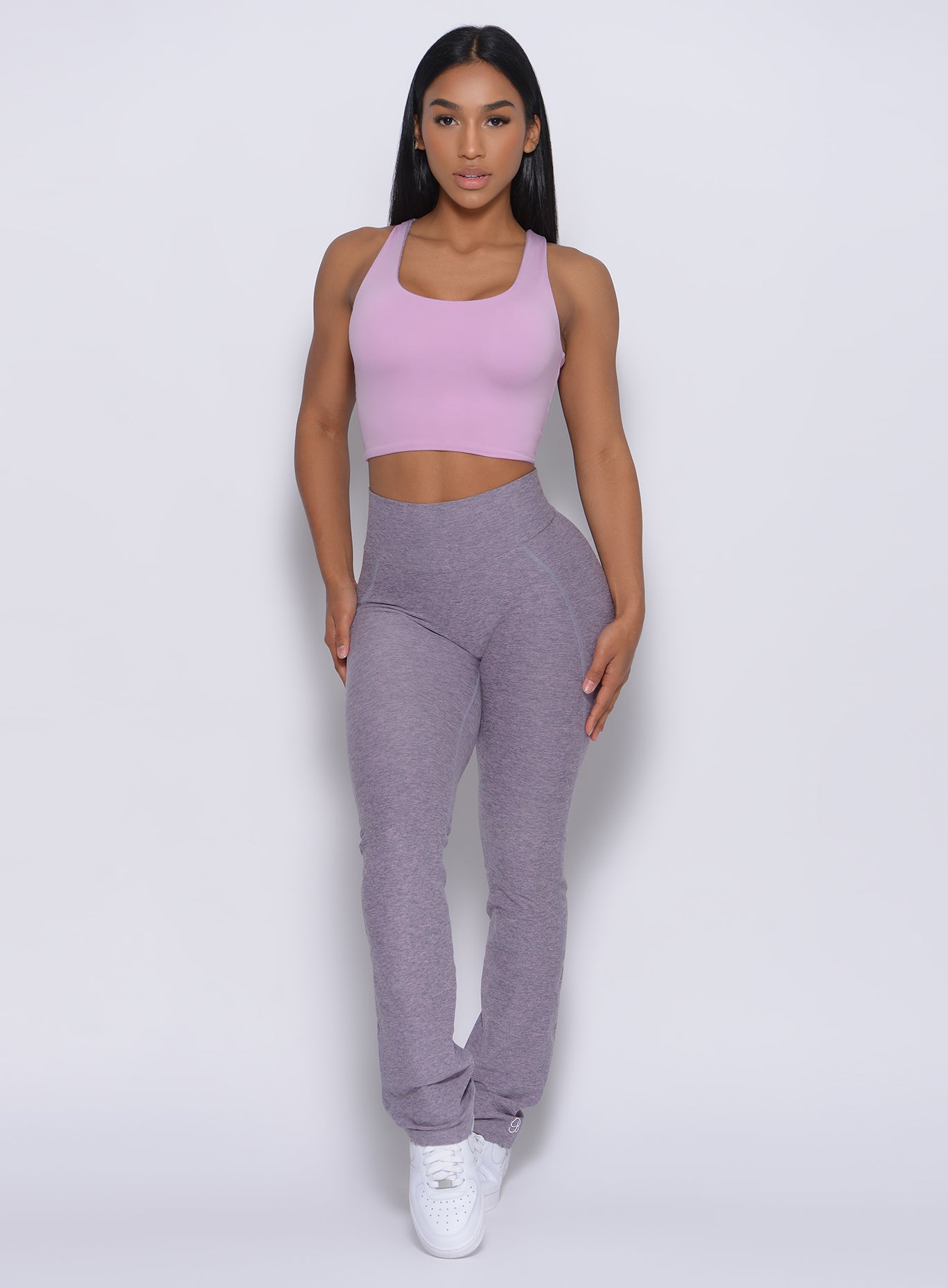 Front profile view of a model in our straight up leggings in orchid color and a bra in blush color