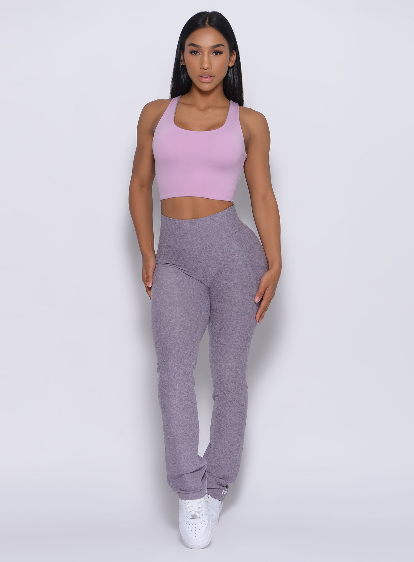 A picture of a model facing forward wearing our reversible long bra in orchid color and a matching leggings