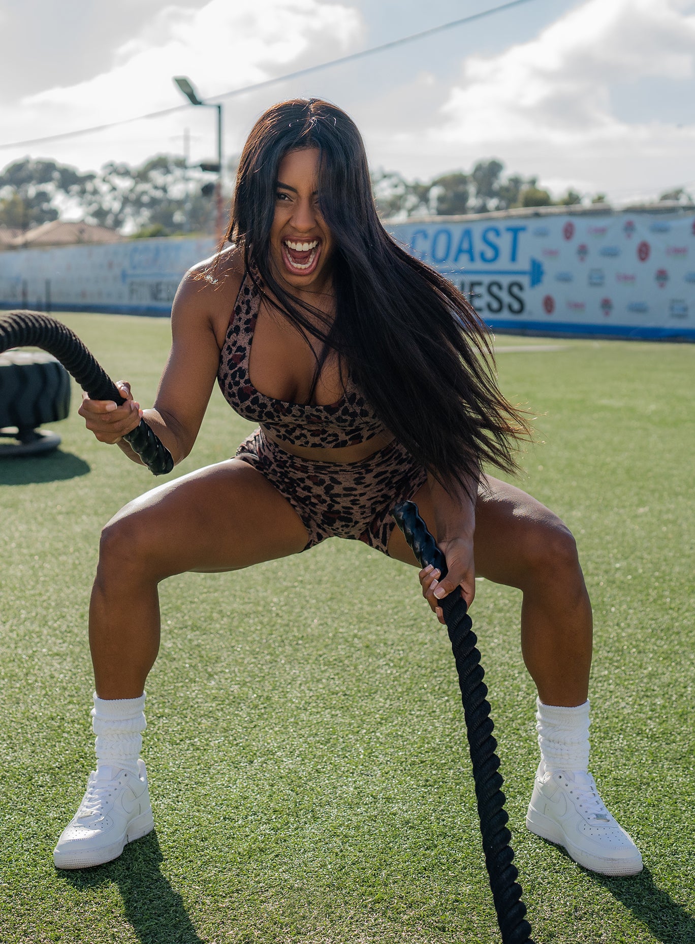 Front profile view of a model holding battle ropes wearing our brown leopard printed toggle shorts sets 