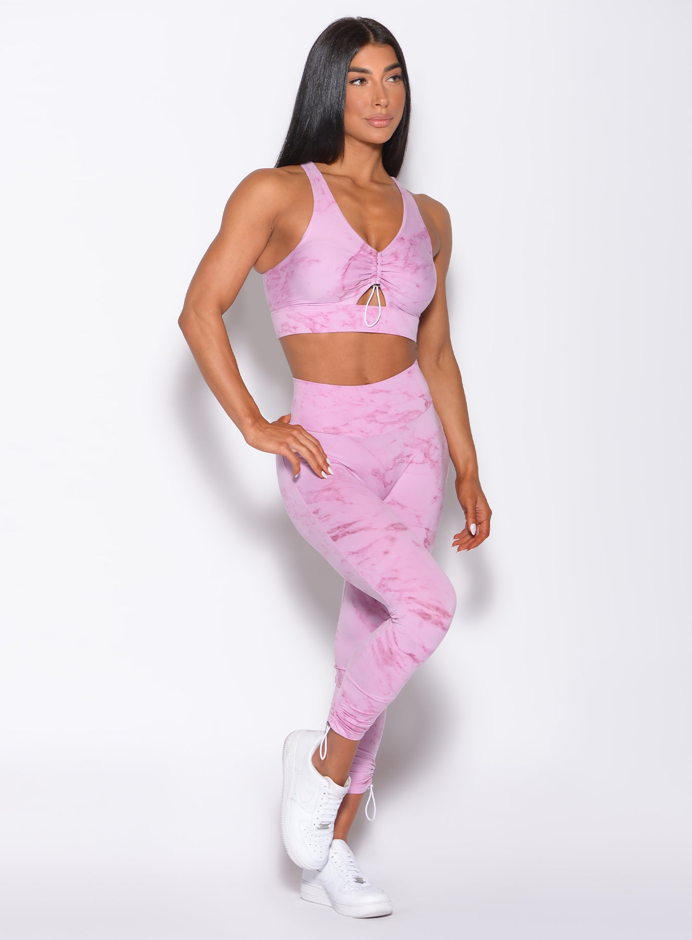 Right side profile view of a model angled right wearing  our adjustable leggings in marble pink color and a matching bra