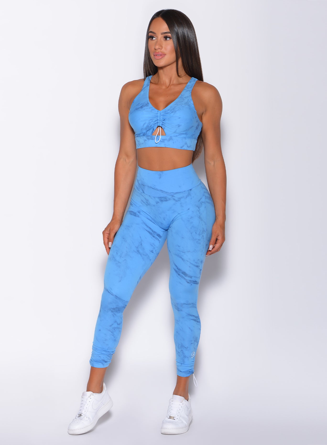 Front profile view of a model in our adjustable leggings in blue marble color and a matching bra 