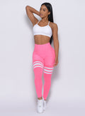 front profile view of a model wearing our Scrunch Thigh High in Hollywood Pink color and a White Sports bra