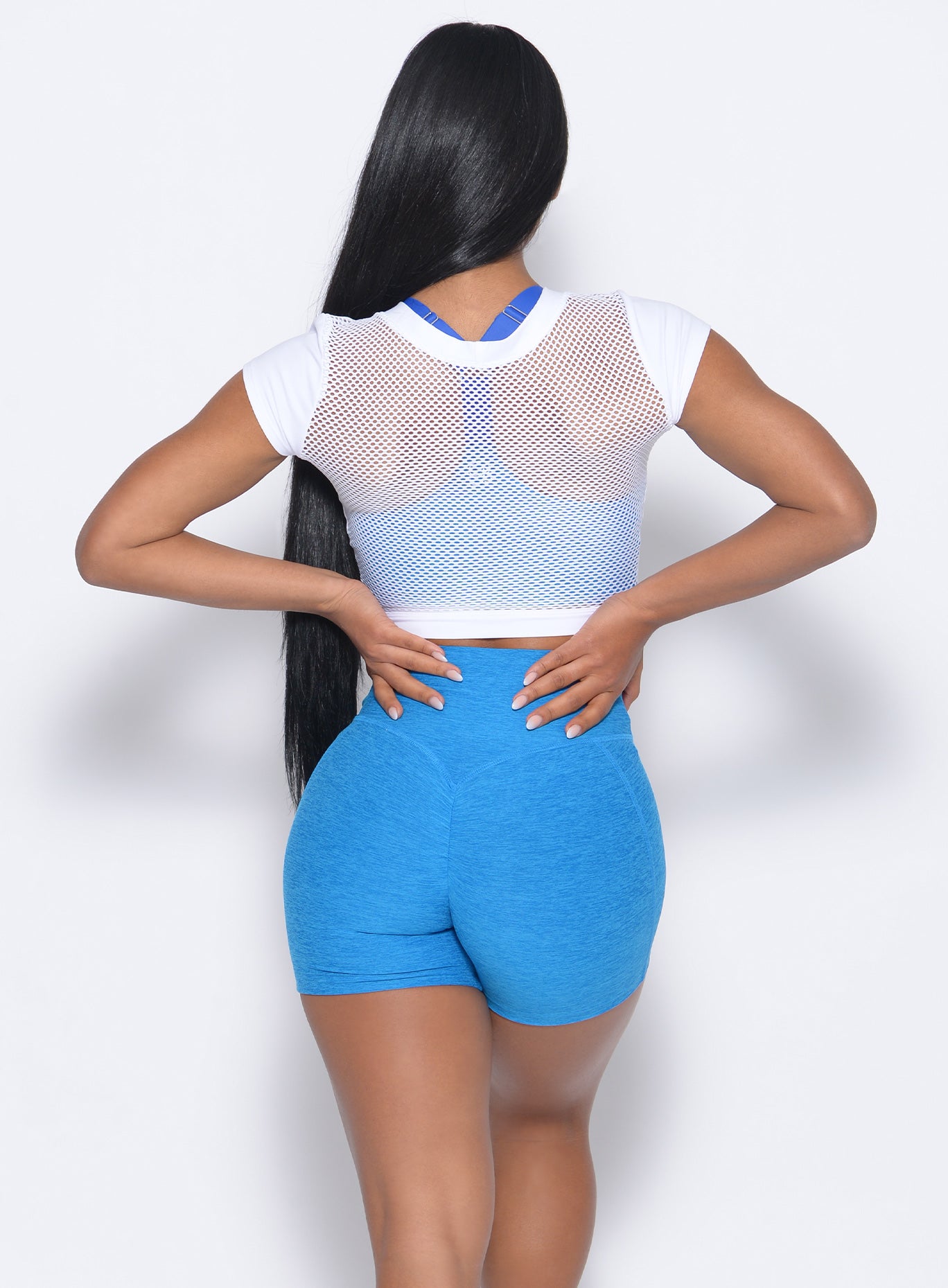 Back view of the model wearing our tiny waist shorts in sky blue and a white tank