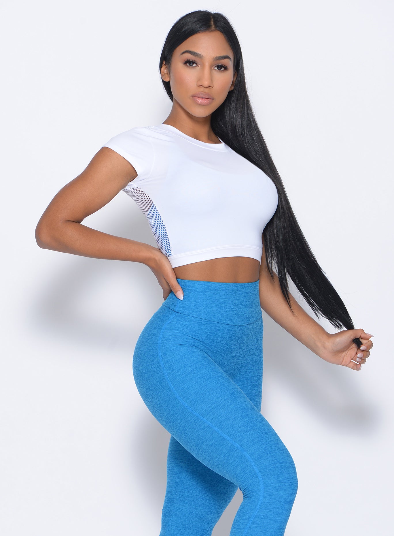 Right side view of the model angled right in our white mesh tee and a high waist leggings