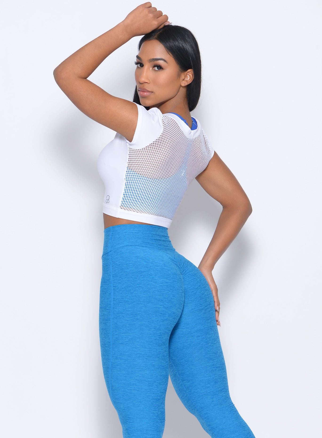 Back view of the model facing to her left  wearing our white mesh tee and a high waist leggings