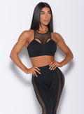 Front profile view of a model in our black Attitude Sports Bra and a matching mohawk leggings 