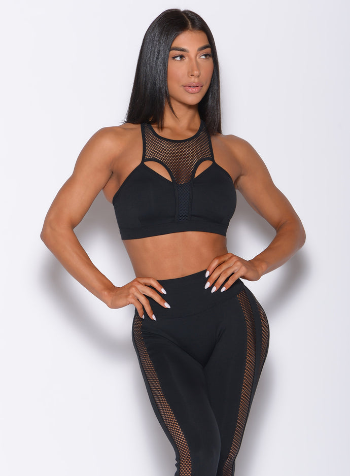 Front profile view of a model in our black Attitude Sports Bra and a matching mohawk leggings 