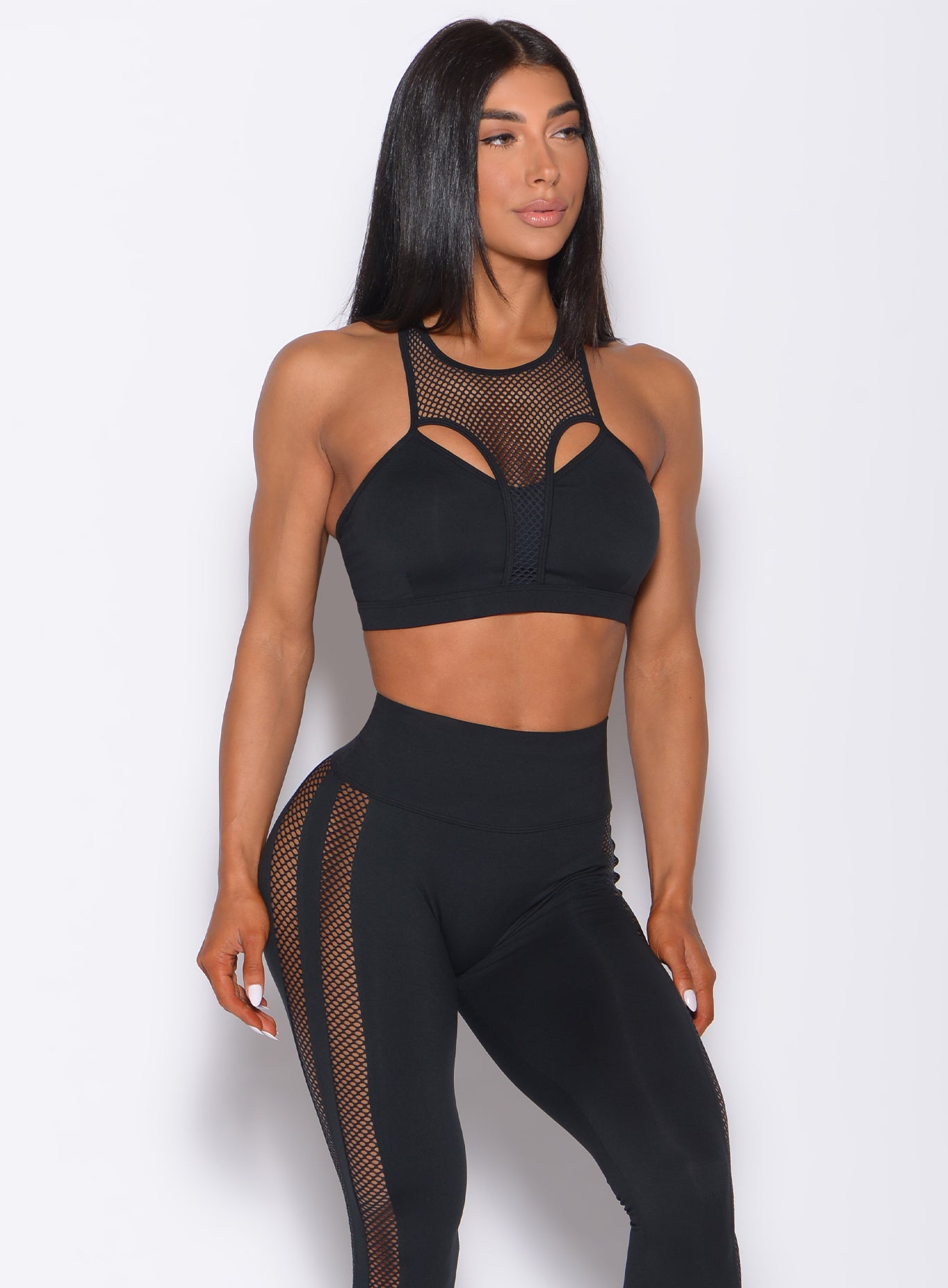 Front profile view of a model wearing our black Attitude Sports Bra and a matching mohawk leggings