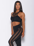 Left side profile view of a model angled to her left wearing our black Attitude Sports Bra and a matching mohawk leggings