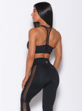 Back profile view of a model in our black Attitude Sports Bra and a matching mohawk leggings