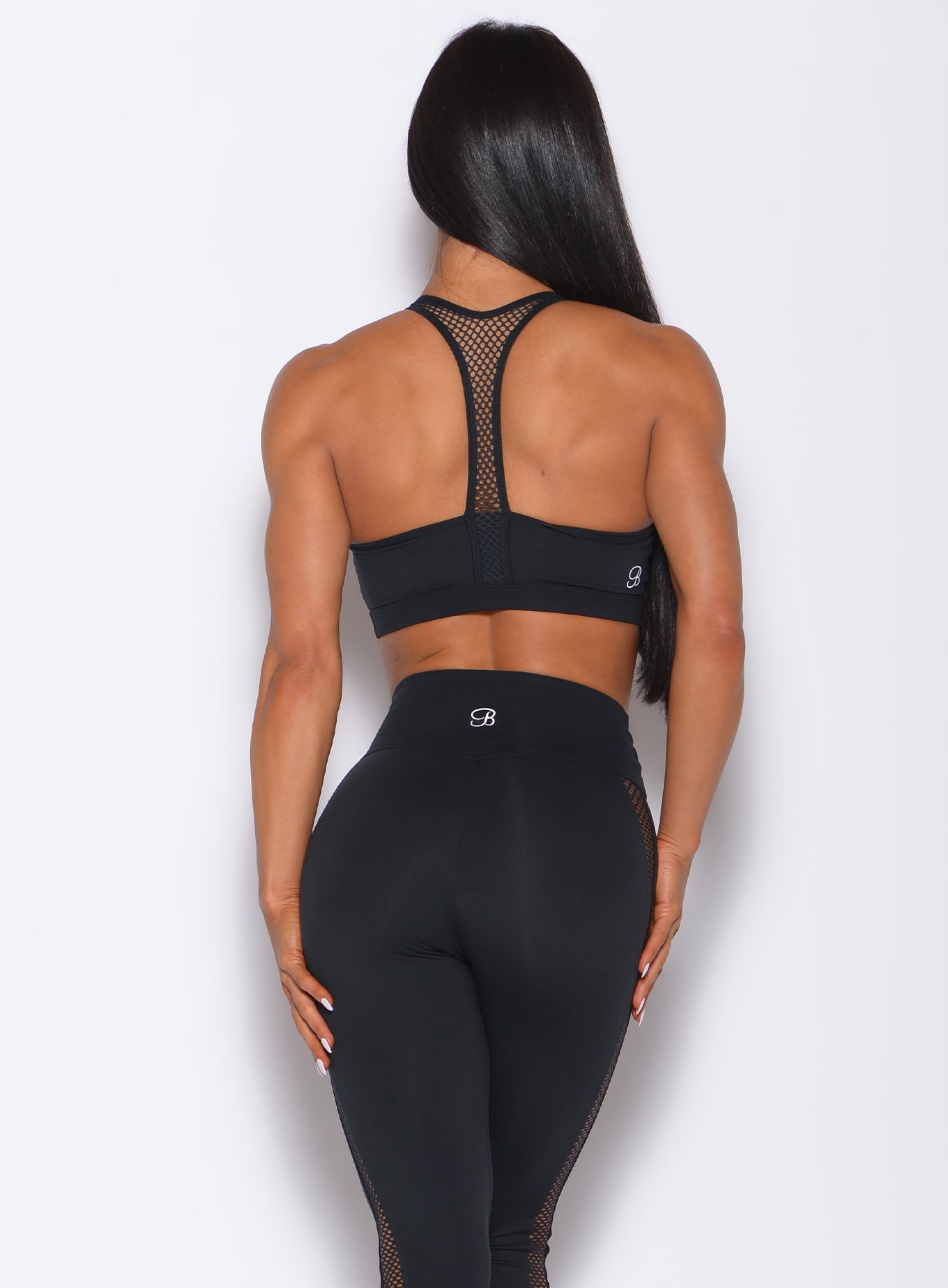 Back profile view of a model wearing our black Attitude Sports Bra and a matching mohawk leggings