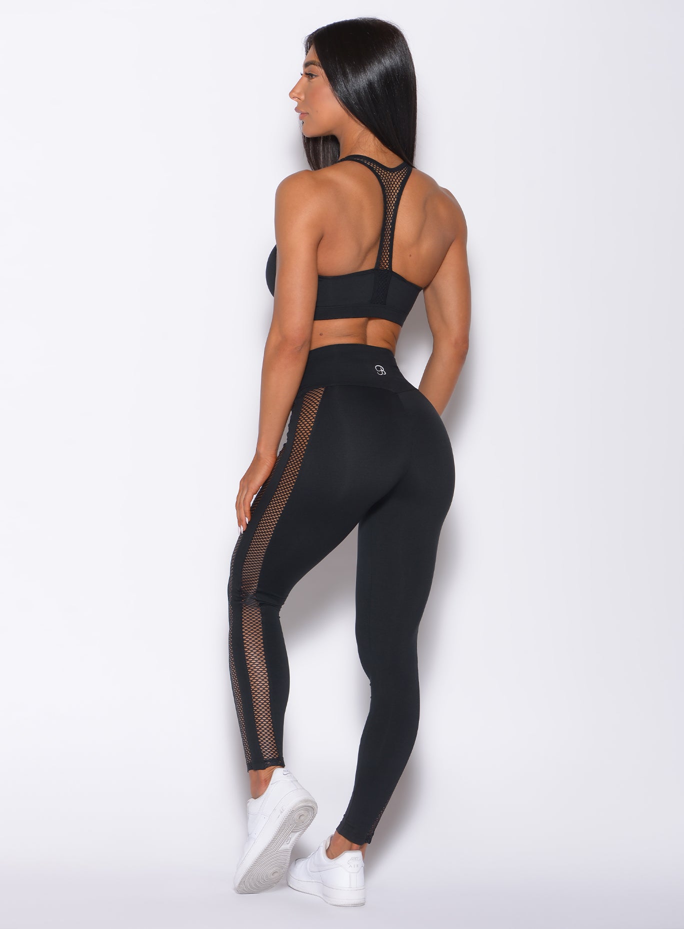 Back profile view of a model facing to her left wearing our black Mohawk leggings and a matching bra